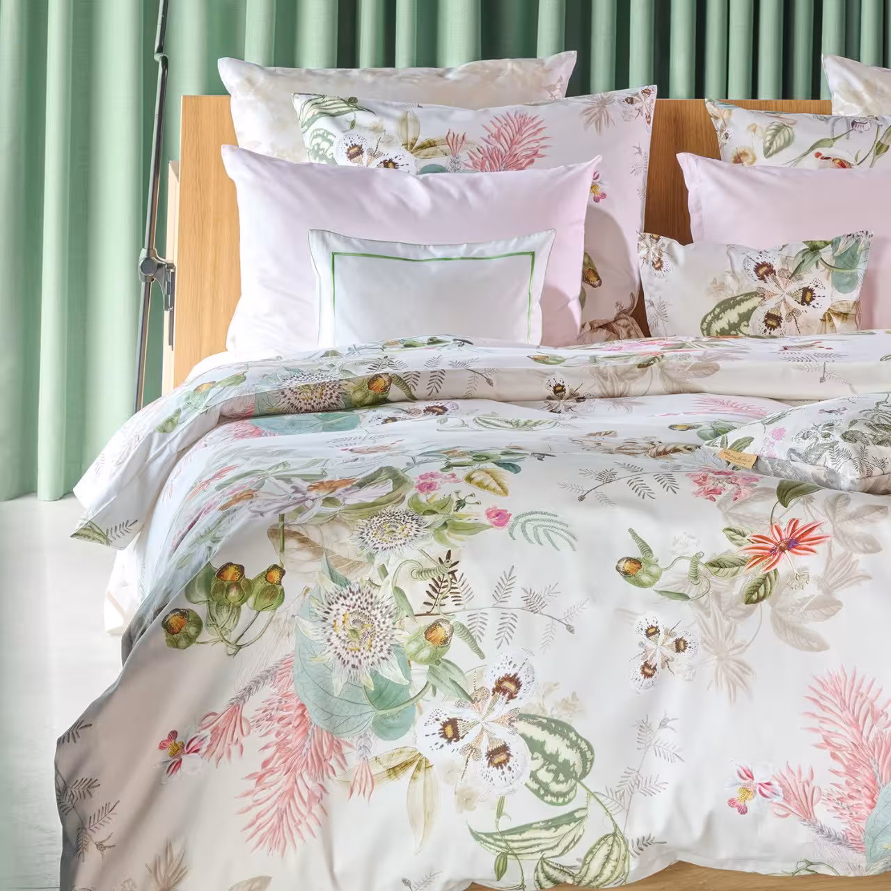 Ausschnitt eines Bettes mit Bettdecke im Blumenmuster und vielen Kissen