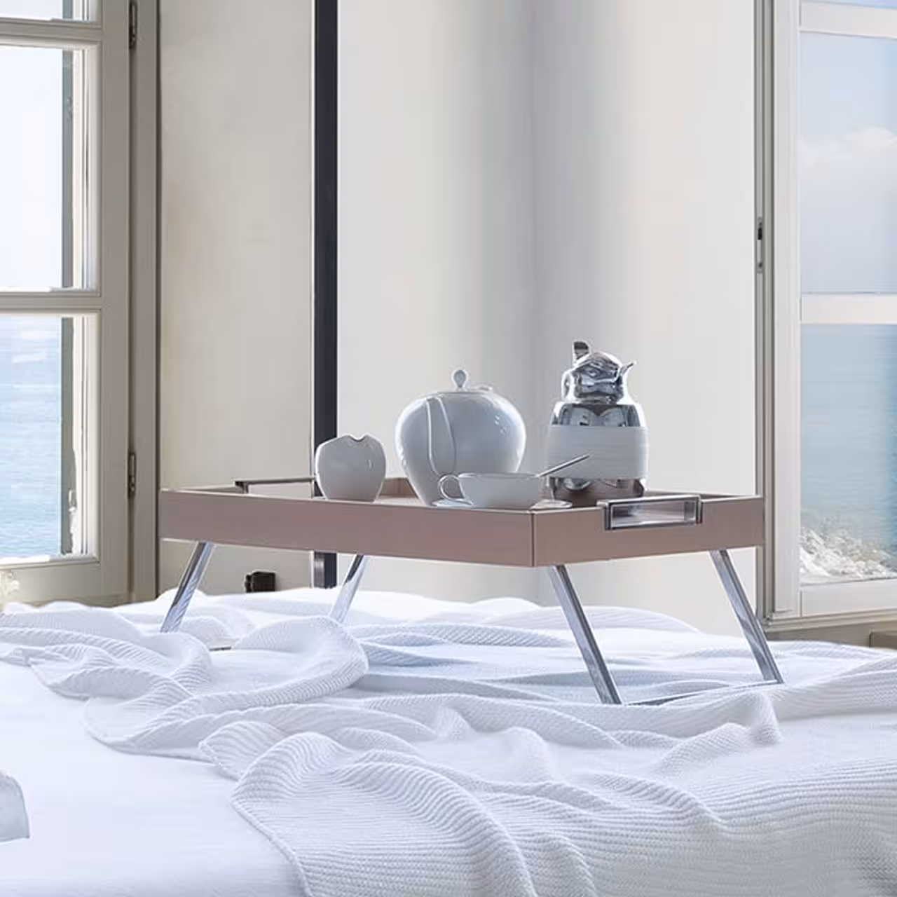 Tablett mit Beinen und Geschirr auf Bett in Schlafzimmer