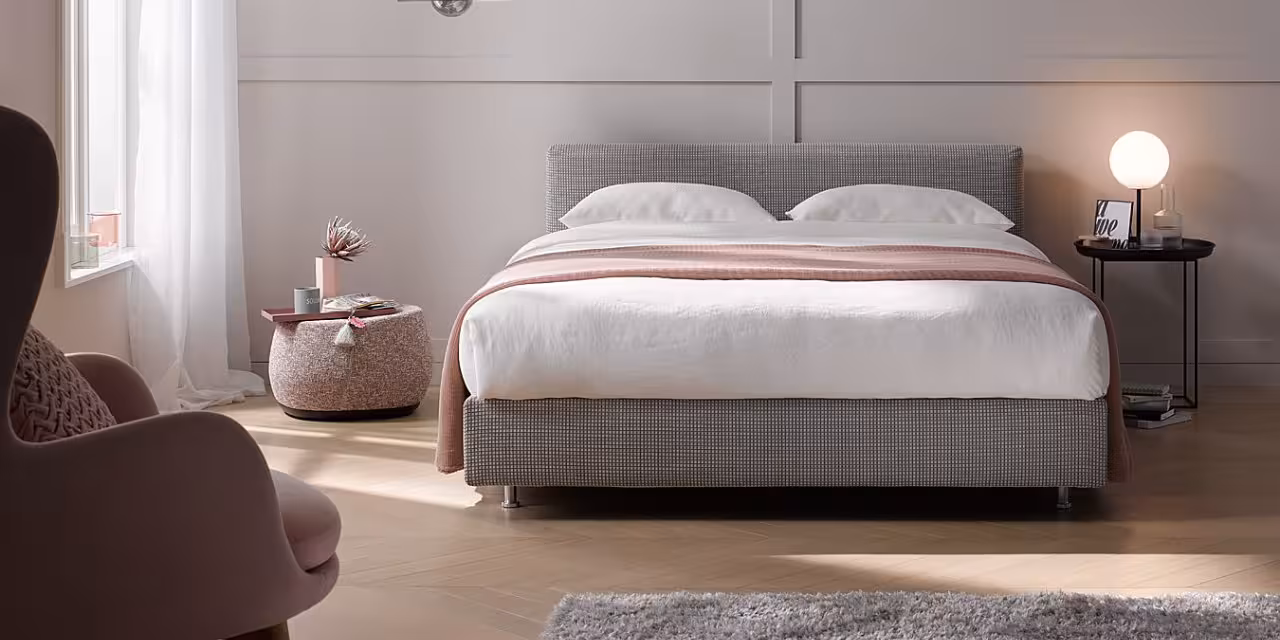 Graues Schramm Boxspringbett in hellem Zimmer mit Altrosa- und Beige-Tönen
