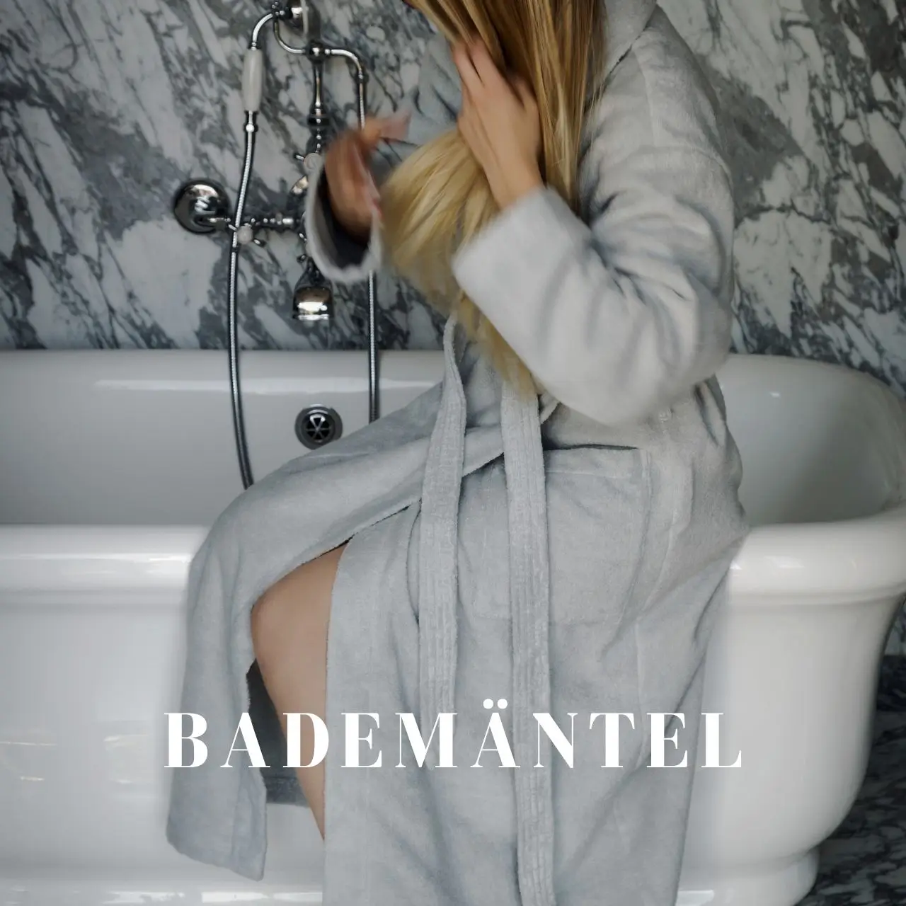 Frau in grauem Bademantel sitzt auf Badewannenrand