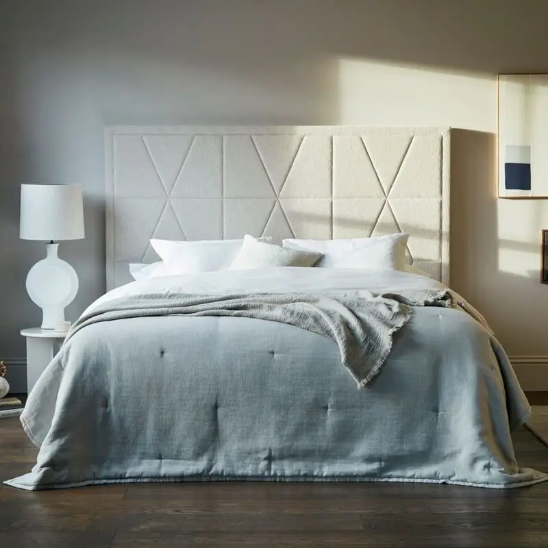 Boxspringbett von Vispring mit hellgrauer Bettwäsche auf dunklem Holzboden