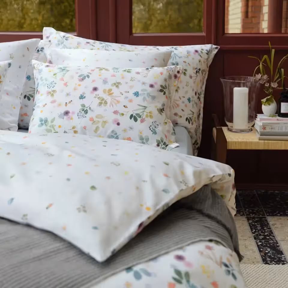 Bettwäschegarnitur Ylvie weiß mit bunten Blumen auf Bett in Schlafzimmer