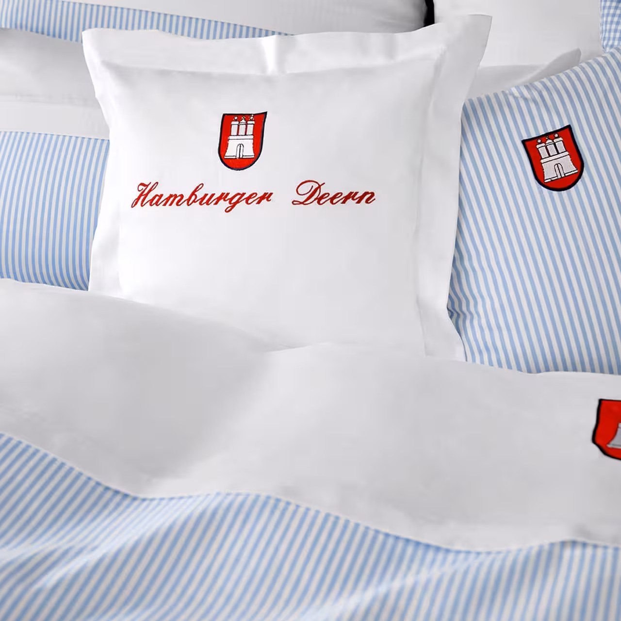 Bettwäschegarnitur Hamburger Deern blau weiß gestreift mit roter Stickerei auf Bett