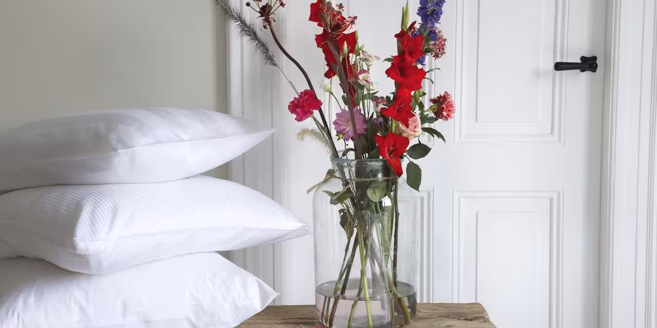 Stapel weiße Kissen neben Blumenstrauß