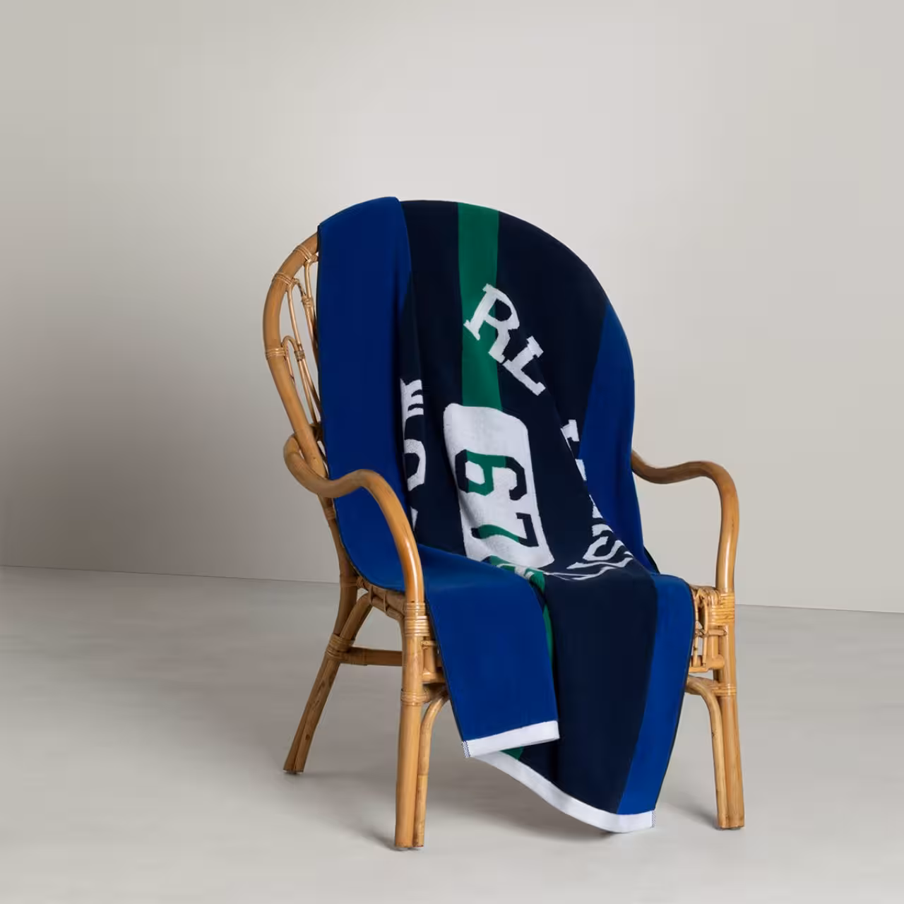 Strandtuch Bates blau. navy, grün weiß auf Korbsessel
