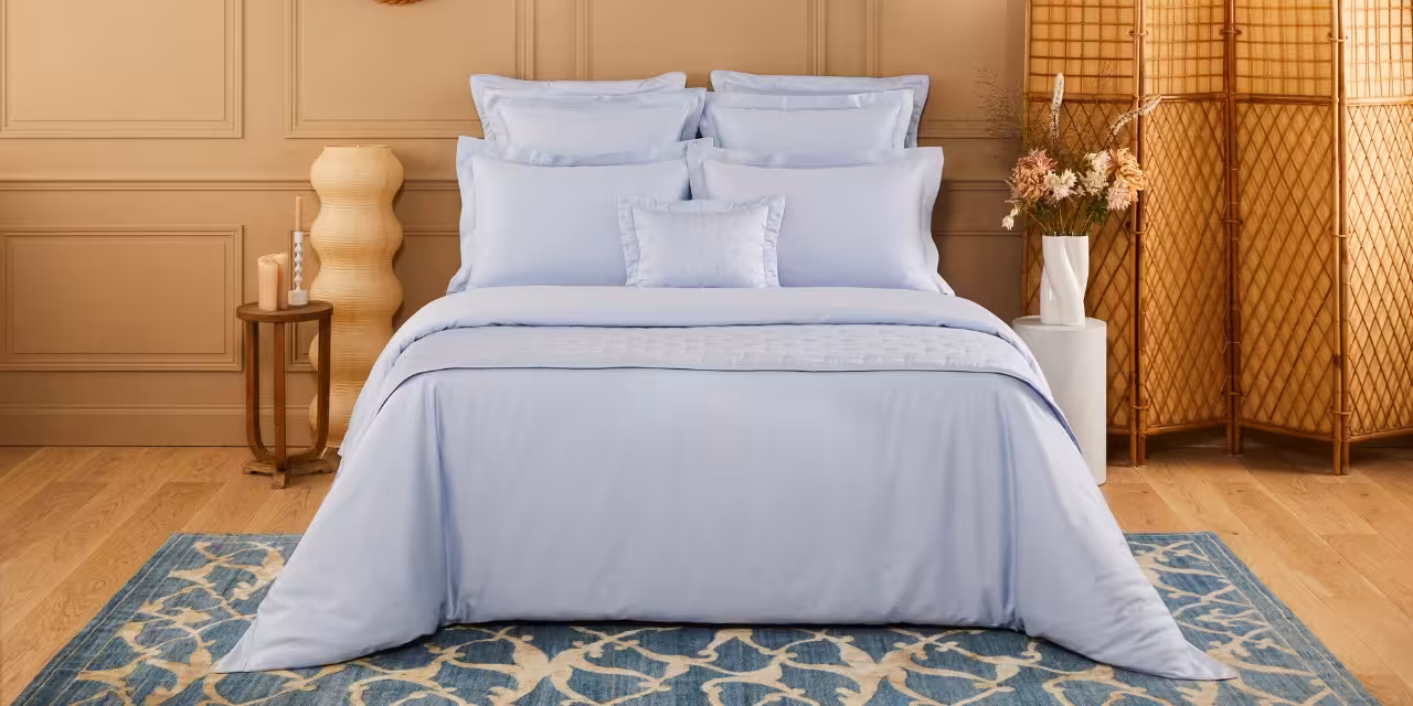 Hellblaues Bett mit Kissen und Decken in Ambiente