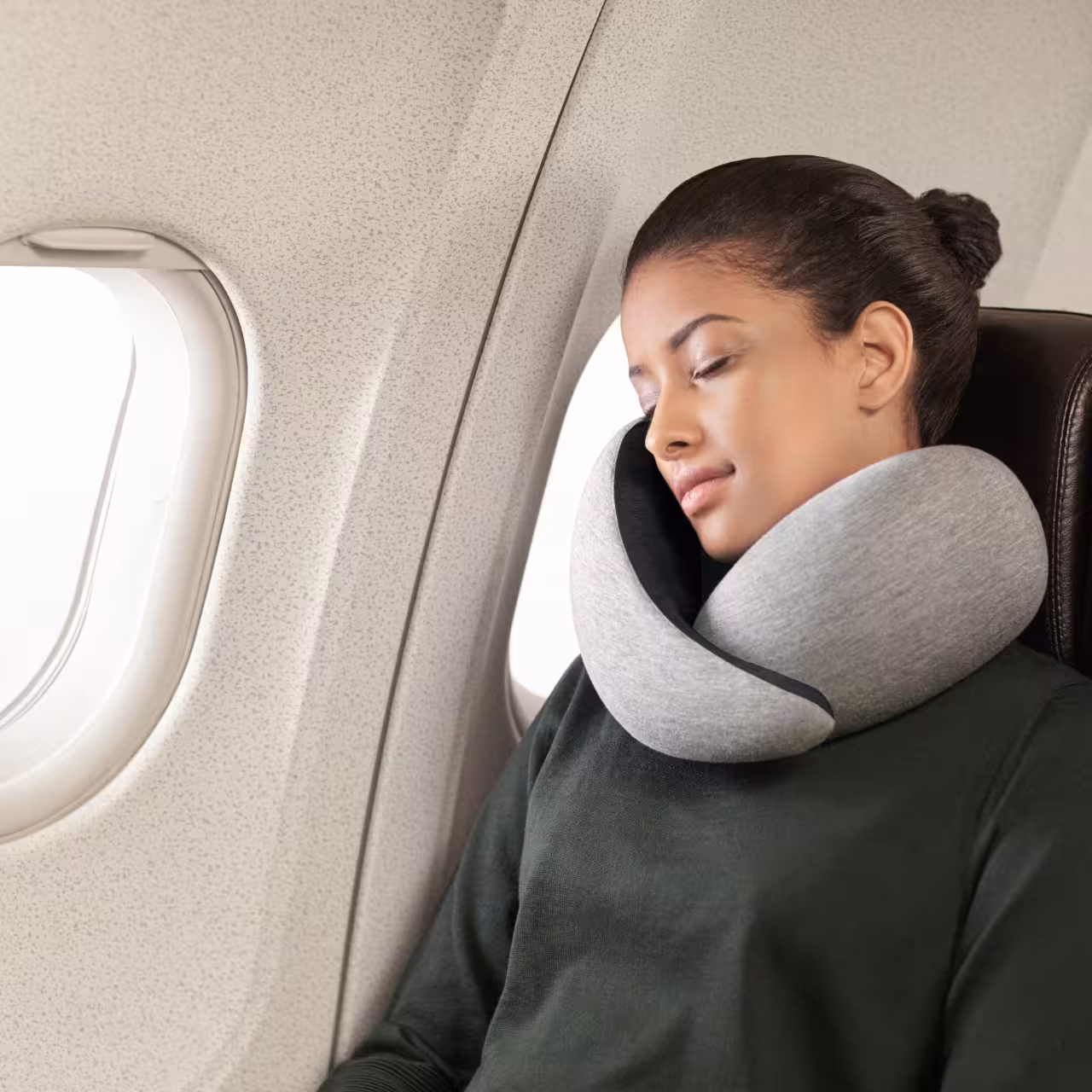 Frau in Flugzeug mit Reisekissen