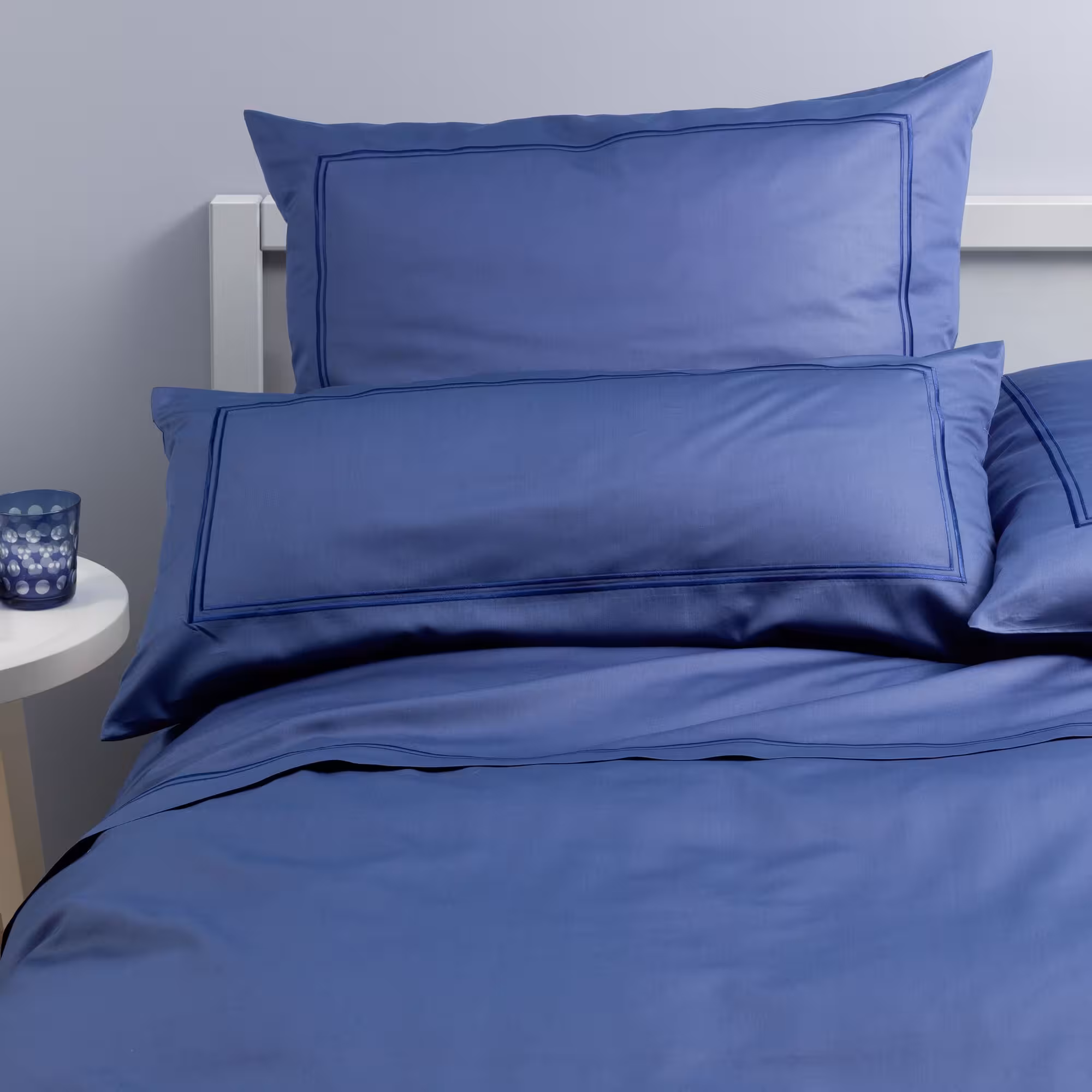 Blaue Bettwäsche mit zwei Kissen auf Bett
