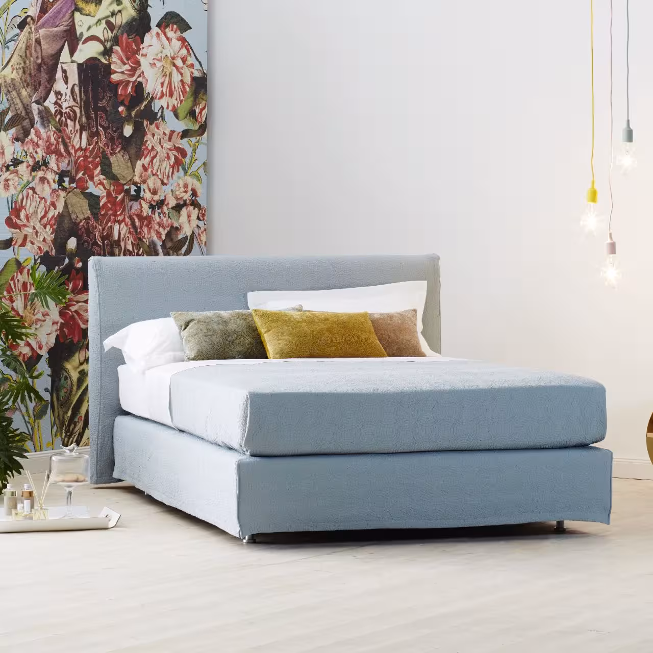 Doppelbett Chill mit blauem Stoff in Schlafzimmer vor floraler Tapete
