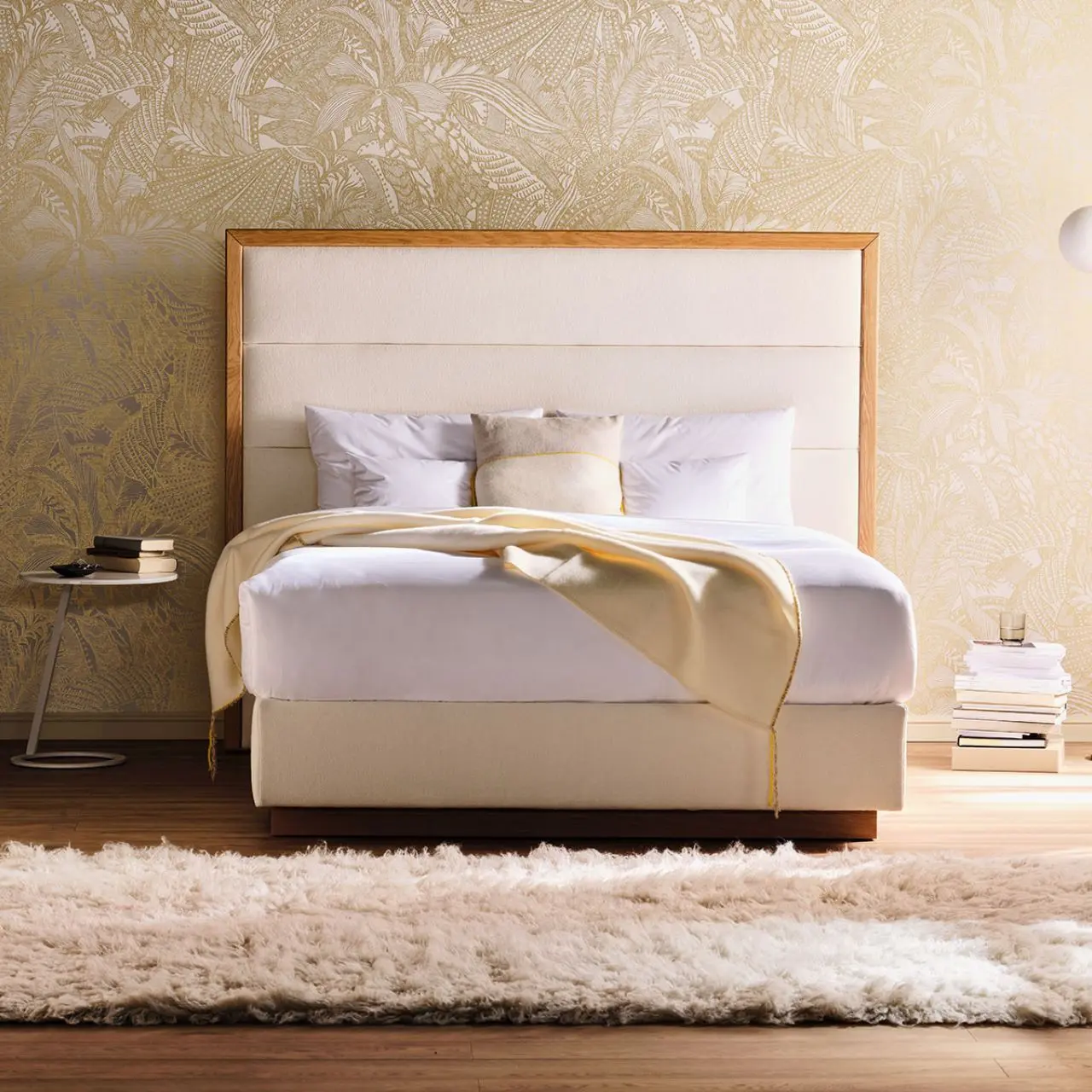 Polsterbett Origins mit hellem Bezug und Holzrahmen am Betthaupt in Schlafzimmer